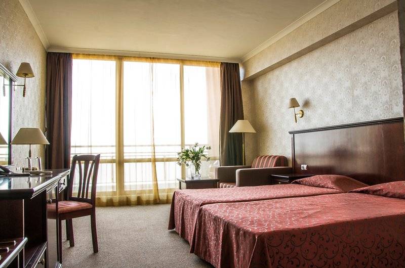 Doppelzimmer im Gladiola Star Hotel mit zwei Betten, Schreibtisch und Fenstern.