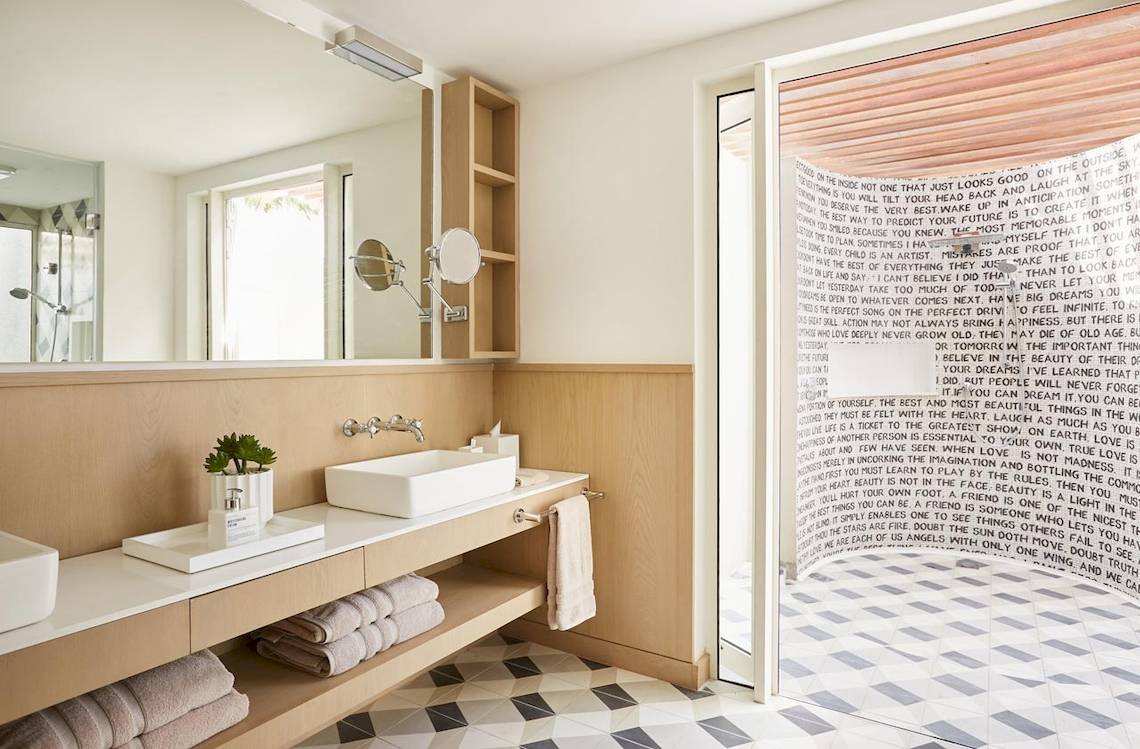 Badezimmer im LUX Grand Gaube Resort & Villas mit heller Beleuchtung, modernen Möbeln und einer Wand mit Text.