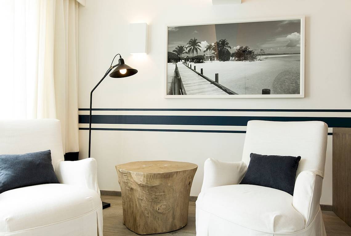 Wohnzimmer im LUX Grand Gaube Resort & Villas mit zwei weißen Sesseln, einem Holztisch und einer Fototapete.