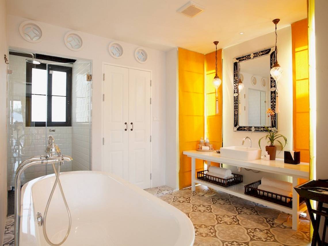 Ein Badezimmer mit einer Badewanne, einem Waschbecken, einem Spiegel und gelben Wänden.