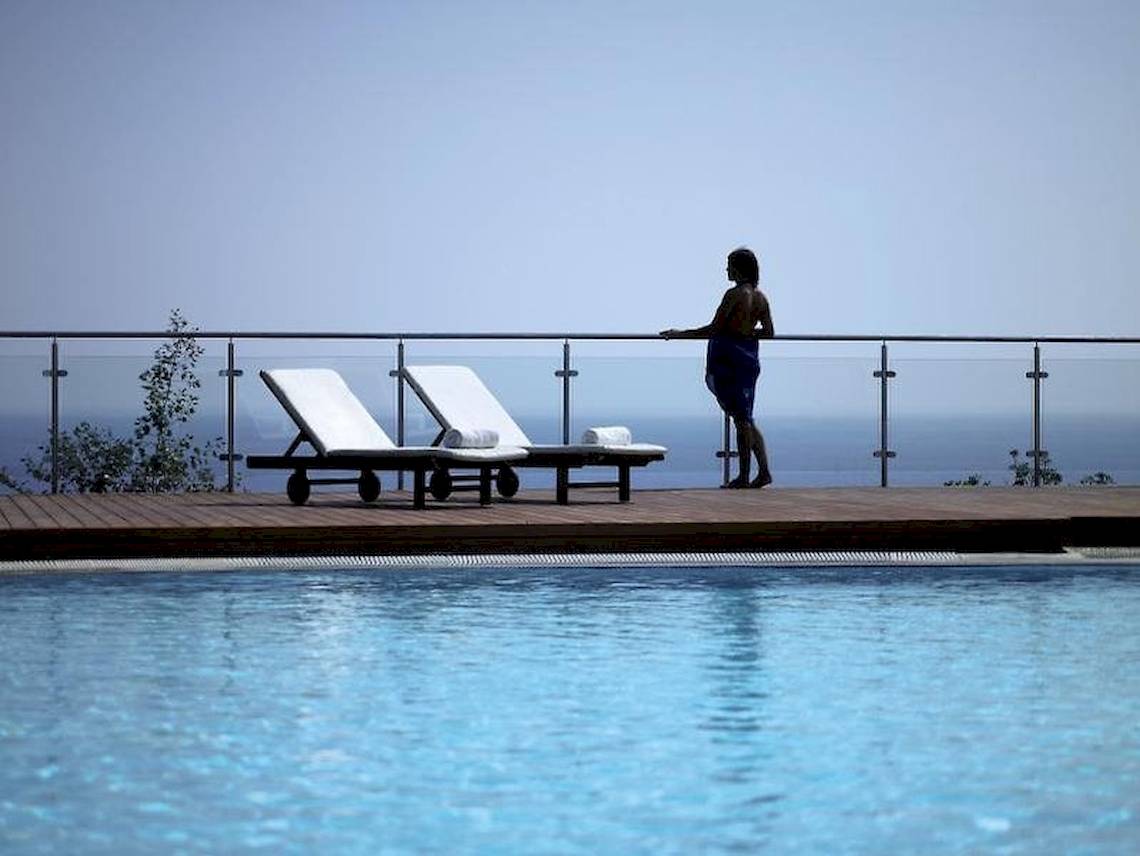 Person am Pool-Geländer des Esperos Village Blue & Spa