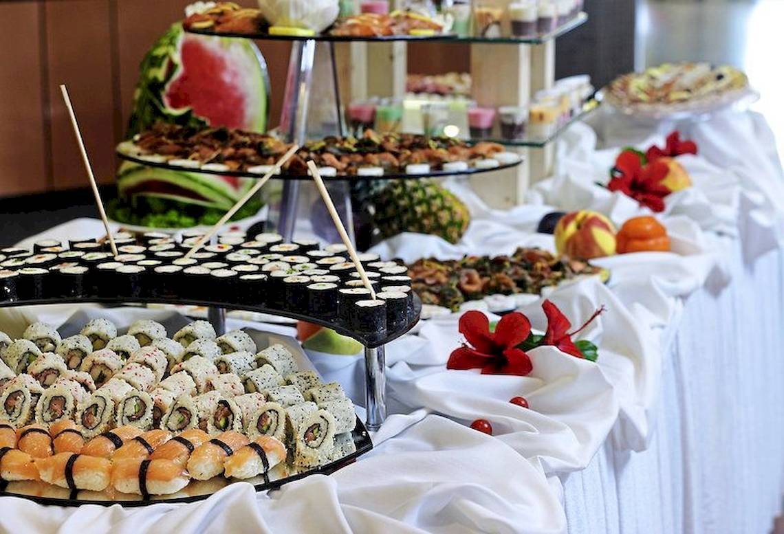 Ein Buffet-Tisch mit verschiedenen Sushi-Rollen und frischen Früchten.
