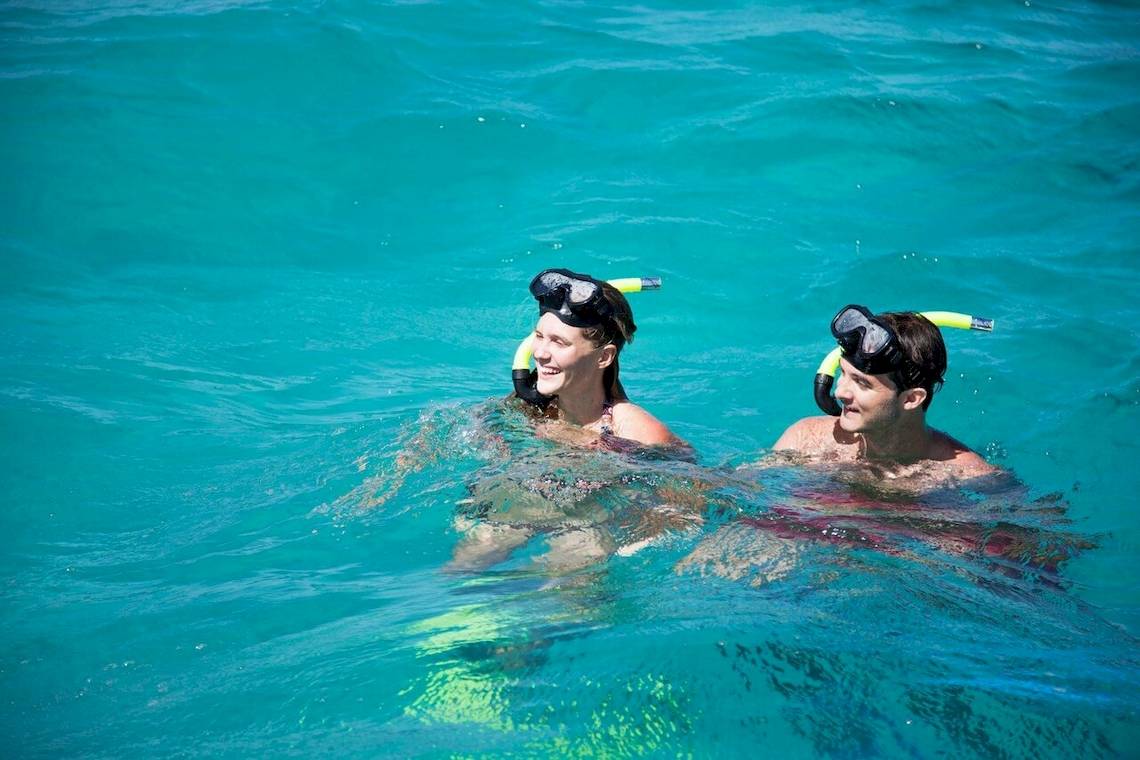 Zwei Personen schnorcheln im kristallklaren Wasser vor dem Veranda Pointe Aux Biches Hotel.