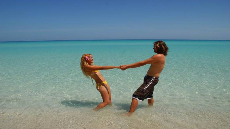Ein Paar steht im klaren Wasser bei Brisas del Caribe und hält sich an den Händen.