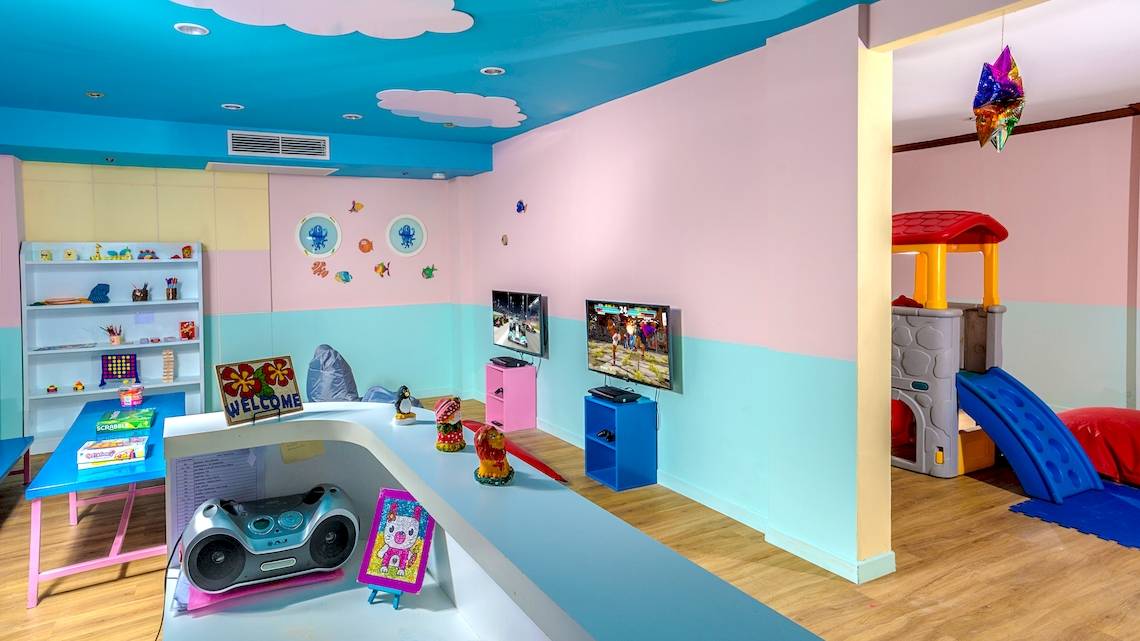 Ein farbenfrohes Kinderzimmer im Best Western Premier Bangtao Beach Resort mit Fernseher, Bücherregal und Spielzeug.
