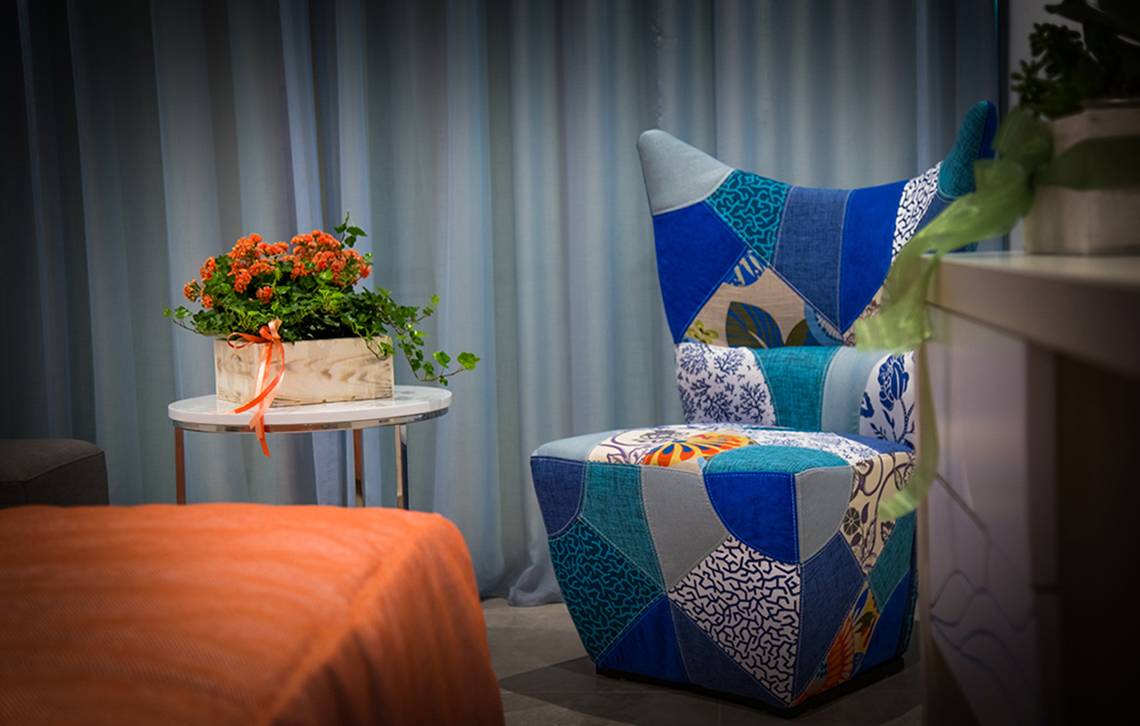 Zimmer im Nicolas Color Hotel mit einem gemusterten Stuhl und einem Tisch mit Blumen.
