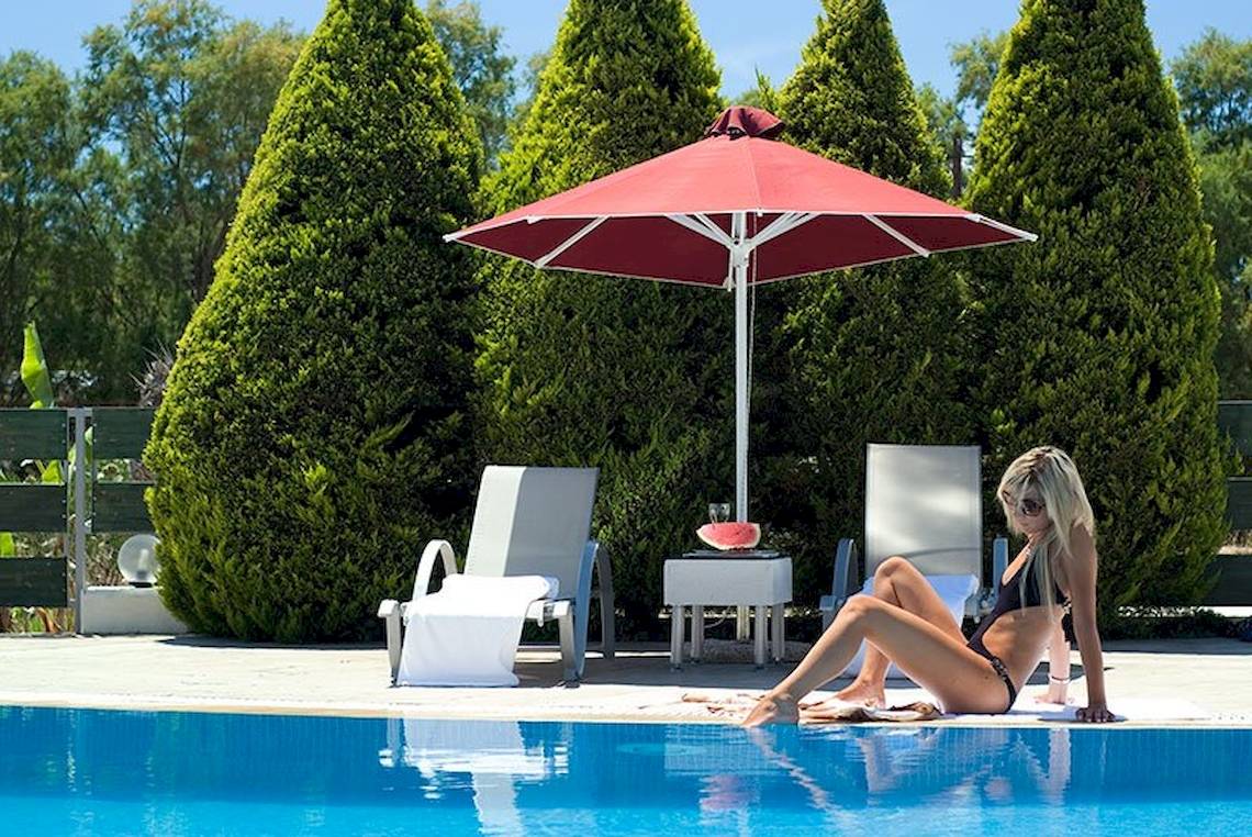 Frau im schwarzen Bikini am Pool unter rotem Sonnenschirm