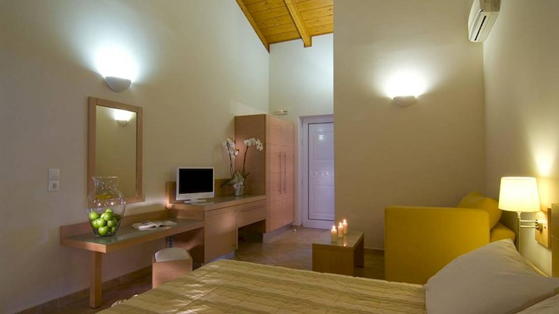 Schlafzimmer im Hotel Verde Al Mare mit Bett, Schreibtisch, Stuhl und gelbem Sofa.
