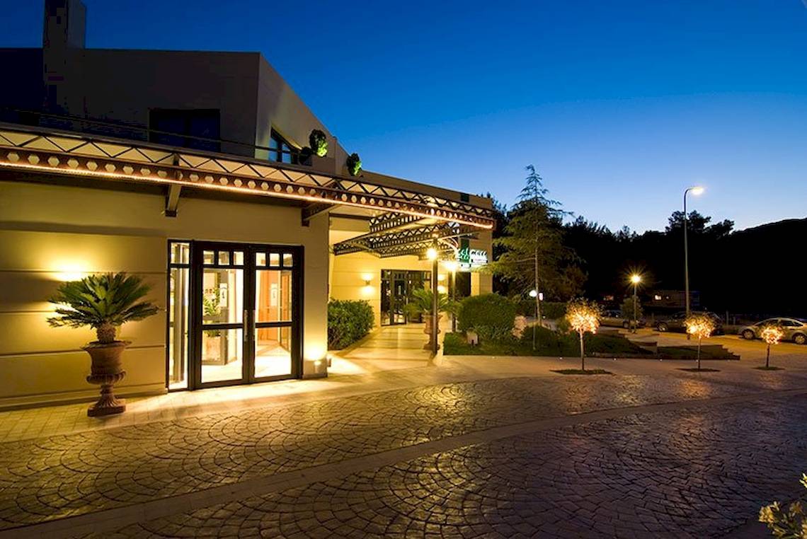 Außenansicht des Verde Al Mare Hotels bei Nacht mit beleuchtetem Eingang und Pflanzen.