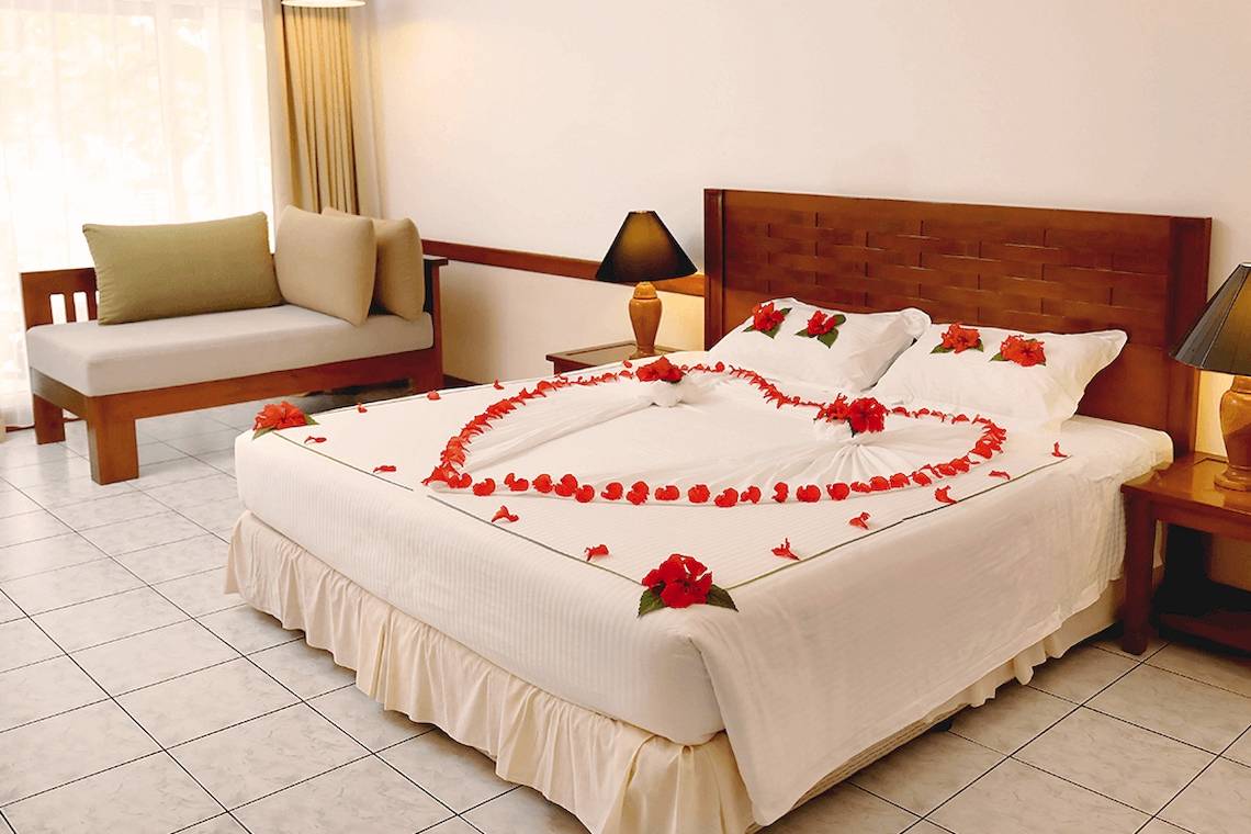 Hotelzimmer in Villa Park, Maldives, mit Bett, das mit roten Blumen dekoriert ist.