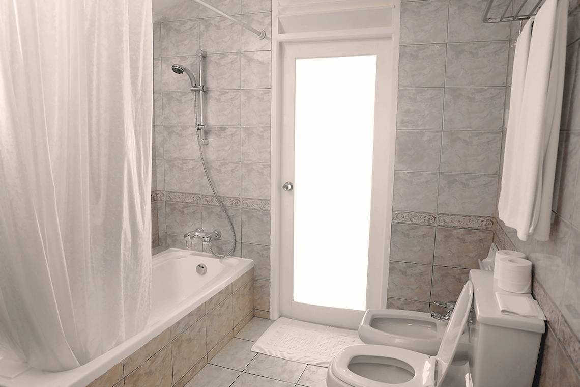Badezimmer der Villa Park, Malediven, mit Badewanne, Dusche, Toiletten und Handtüchern.