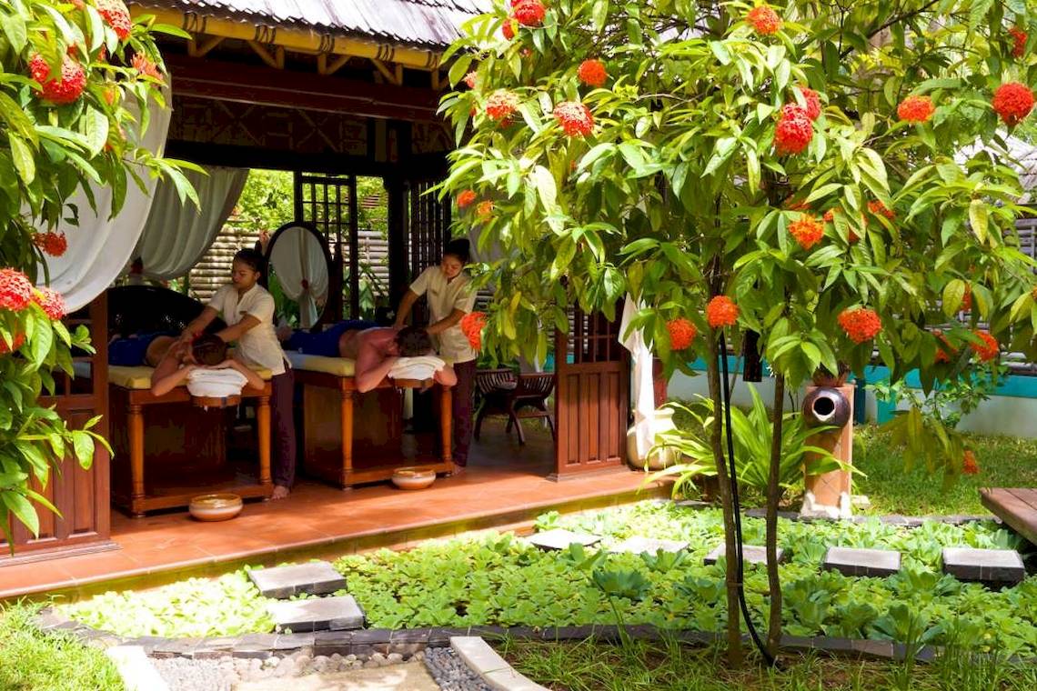 Massage im Freien im Villa Park, Malediven, mit zwei Kunden und Therapeuten unter einem schattigem Pavillon.