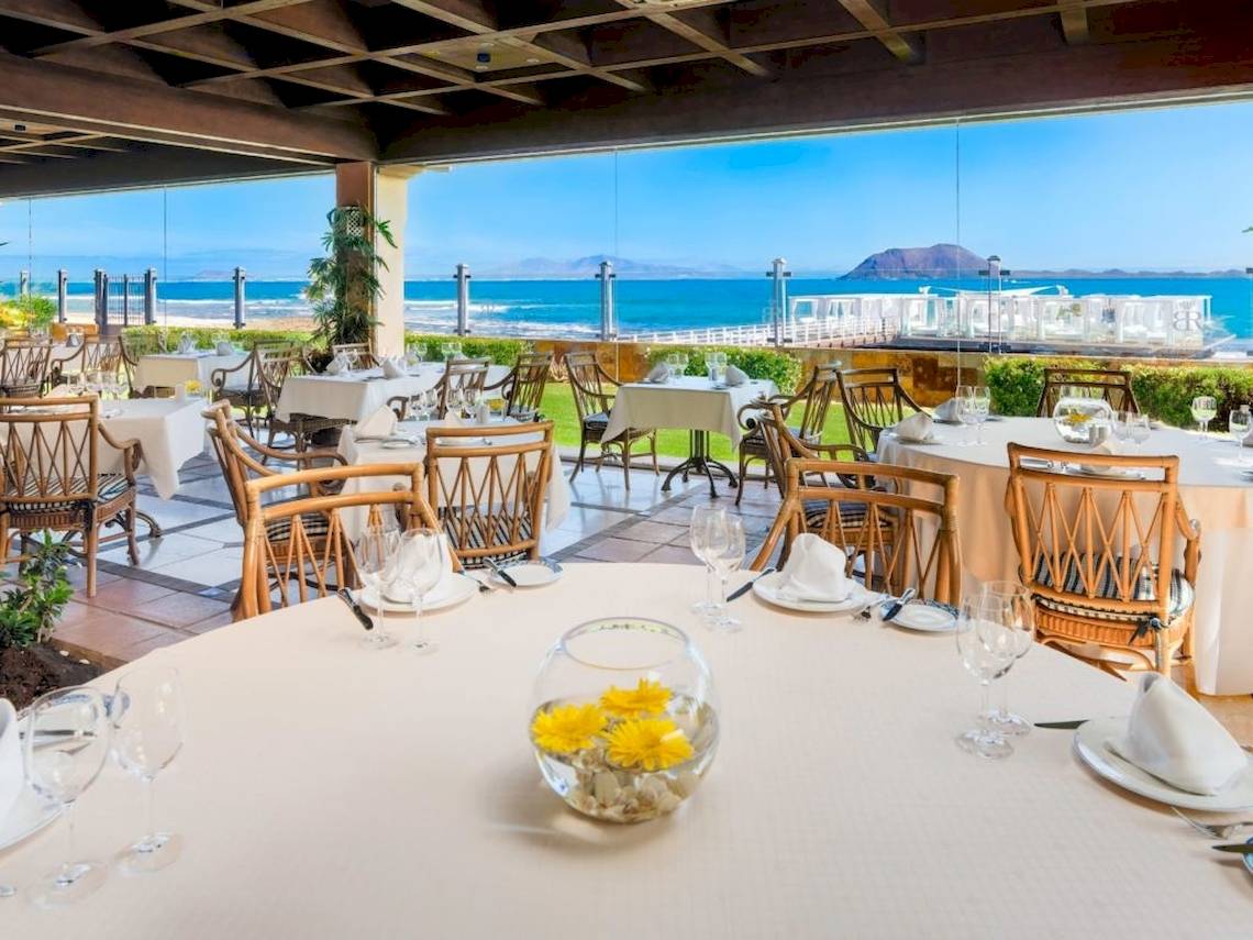 Innenansicht des Restaurants im Secrets Bahia Real Resort & Spa mit Blick auf das Meer.