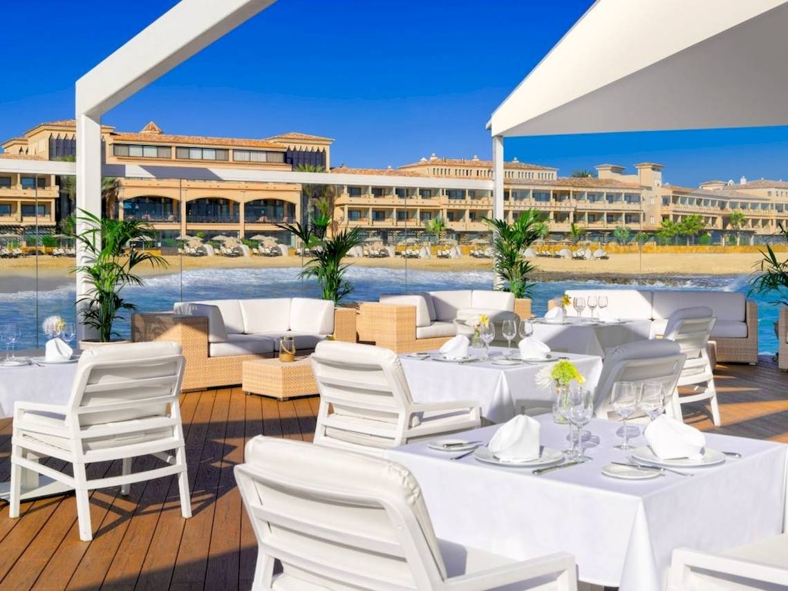 Gedeckter Tisch auf einer Terrasse am Strand vor dem Secrets Bahia Real Resort & Spa Hotel.