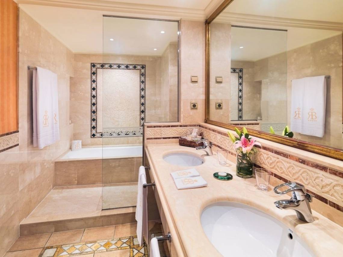Luxuriöses Badezimmer mit Doppelwaschbecken, Badewanne, Spiegel und Marmorboden.