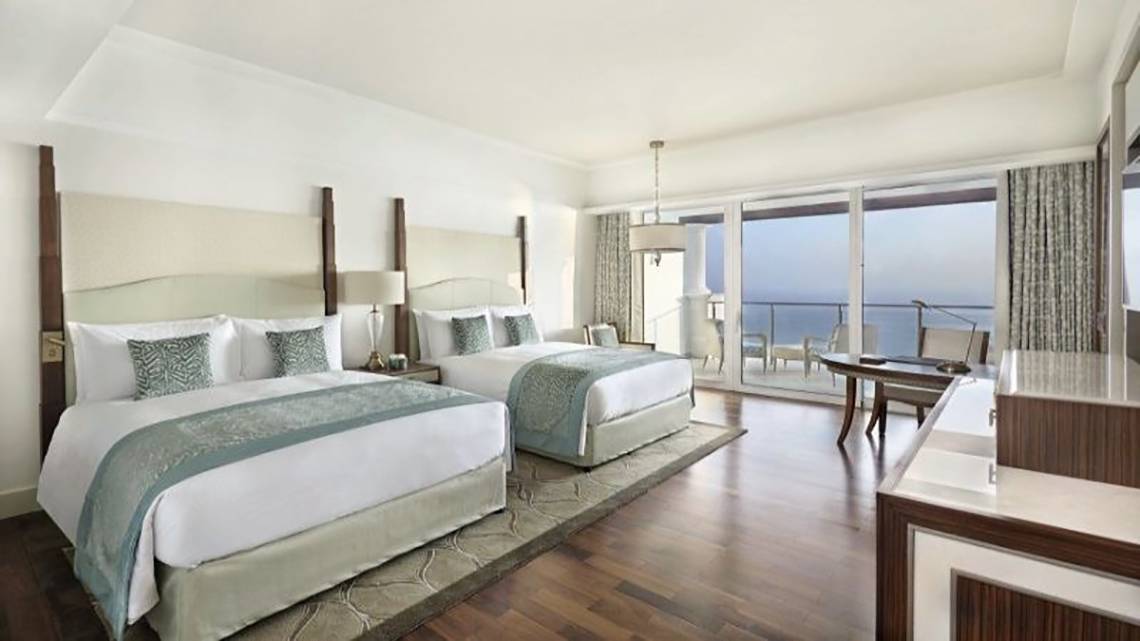 Innenansicht der Suite im Waldorf Astoria Dubai Palm Jumeirah mit zwei Betten, Meerblick und modernem Interieur.