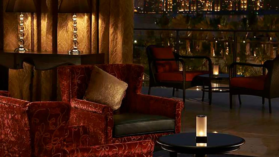 Lounge-Innenansicht des Waldorf Astoria Dubai Palm Jumeirah mit rotem Möbeln und Aussicht auf die Stadt.