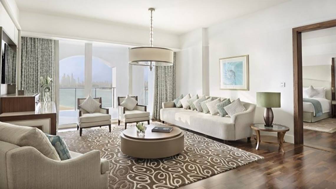 Wohnzimmer im Waldorf Astoria Dubai Palm Jumeirah mit weißen Möbeln, einem großen Fenster und Blick auf das Meer.
