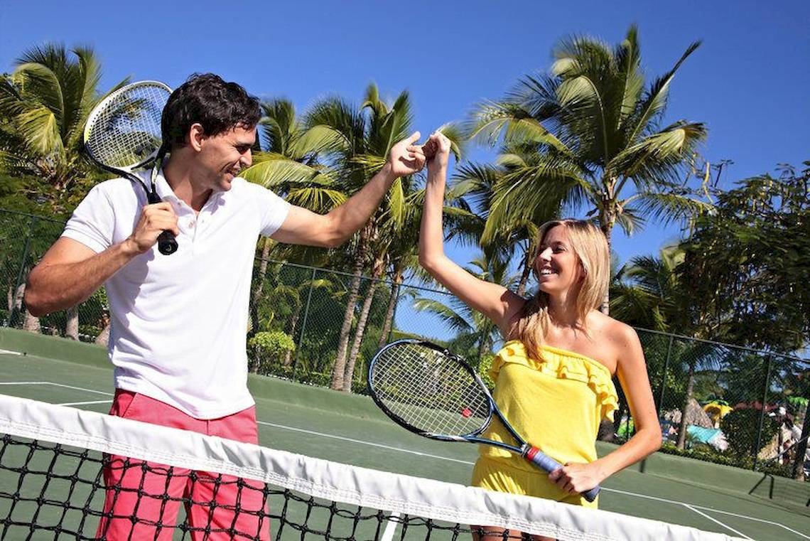 Tennisspieler auf einem Tennisplatz im Freien, beide mit Tennisschlägern, scheinen ein Spiel beendet zu haben.