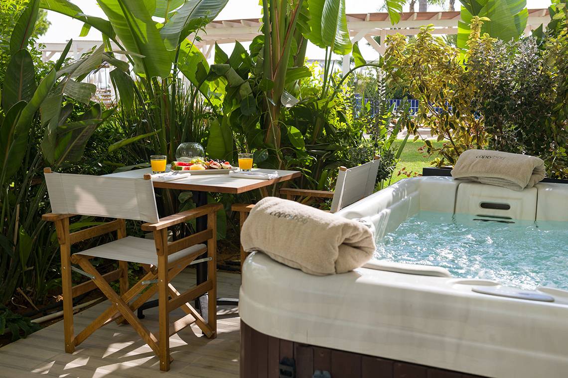 Whirlpool auf der Terrasse des Capo Bay Hotels mit grünen Pflanzen im Hintergrund.
