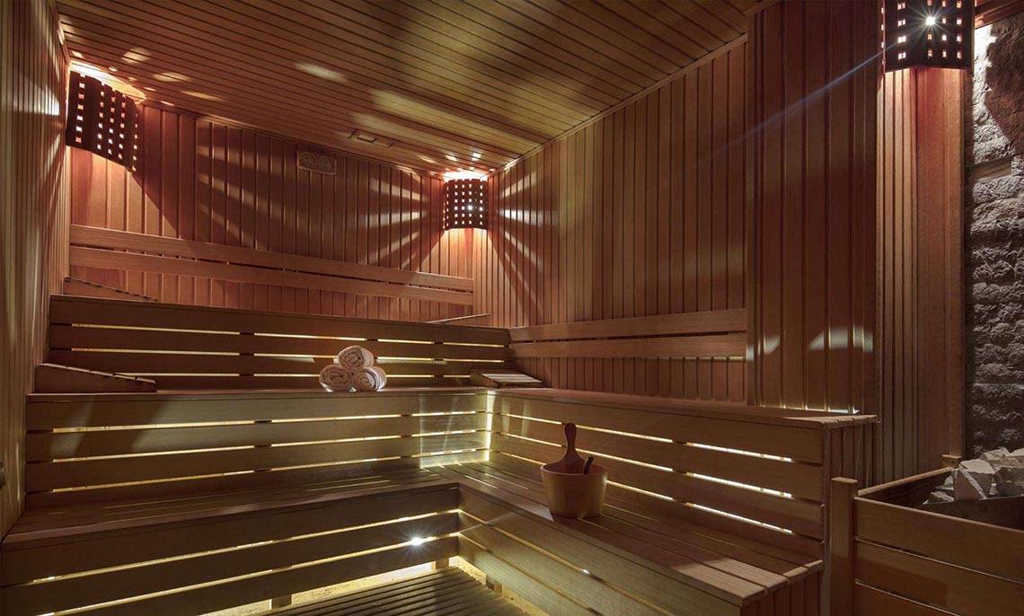 Sauna im Magic Life Belek Hotel mit Holzbänken, Handtüchern und Beleuchtung.