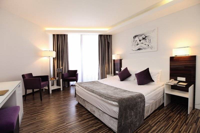 Hotelzimmer im Palm Wings Ephesus Beach Resort mit einem Bett, zwei Sessel und einem Schreibtisch