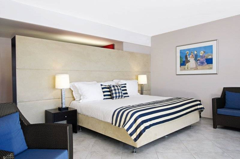 Schlafzimmer im Avila Beach Hotel mit Doppelbett, Nachttischen und Wandgemälde.