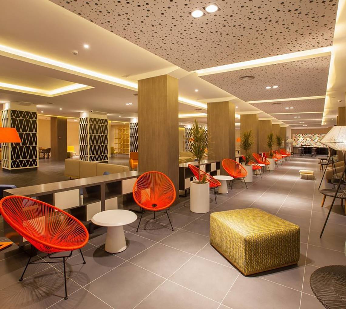 Innenbereich des Abora Catarina Hotel mit roten Stühlen und Tischen, Pflanzgefäßen und gefliestem Boden.