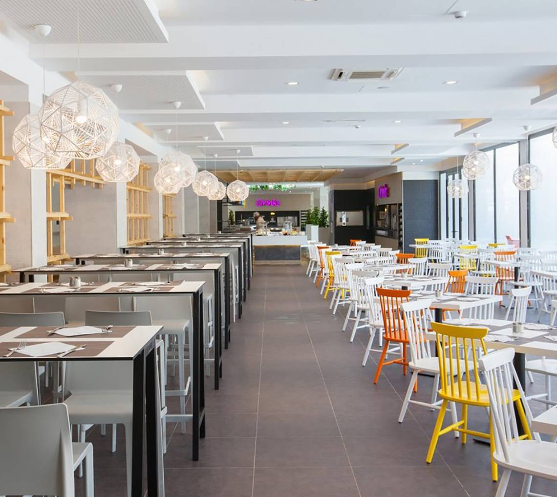Innenansicht des Restaurants im Abora Catarina Hotel von Lopesan Hotels, mit weißen und bunten Stühlen und Tischen