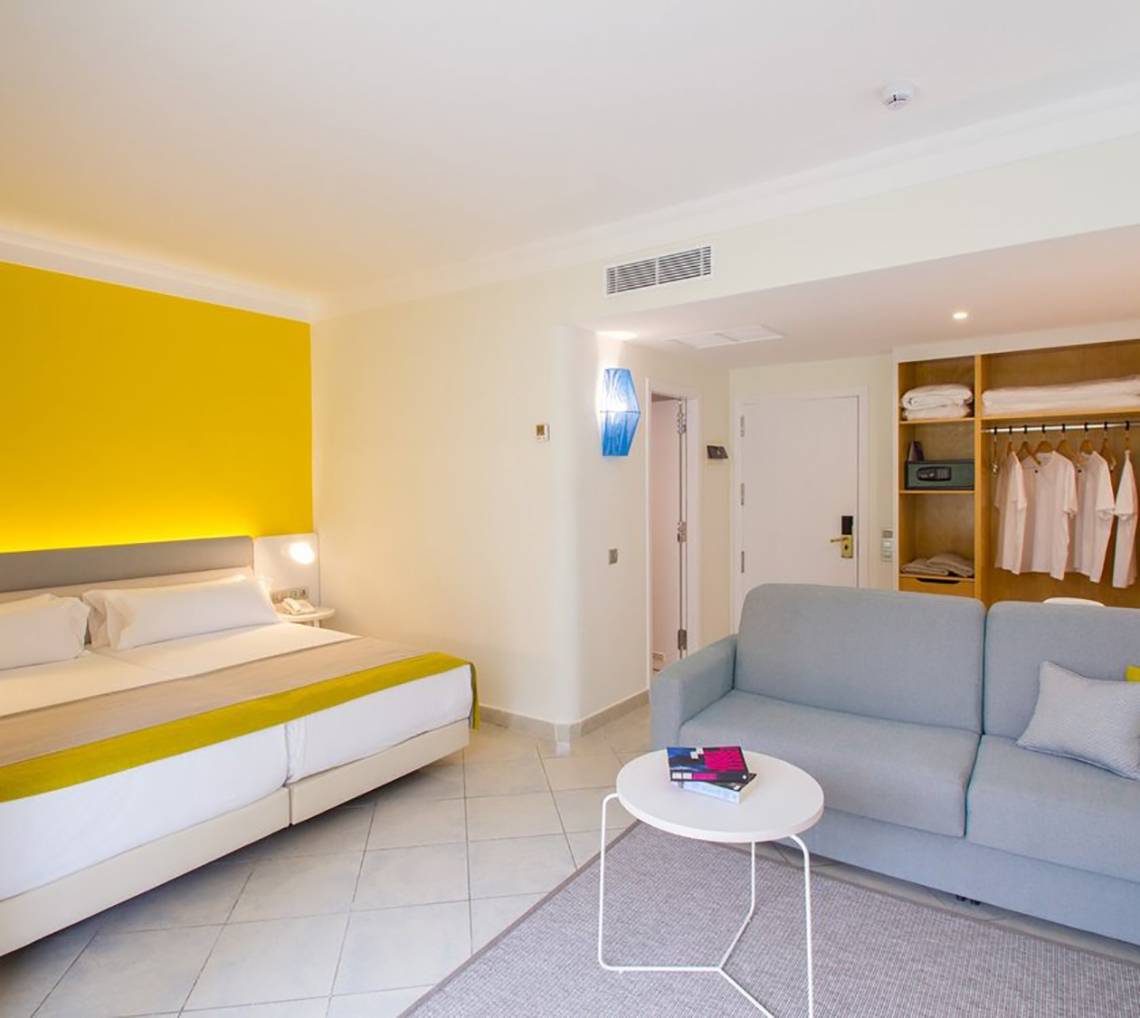 Innenansicht eines Zimmers im Abora Catarina Hotel mit Bett, Sofa, Tisch und Kleiderschrank.