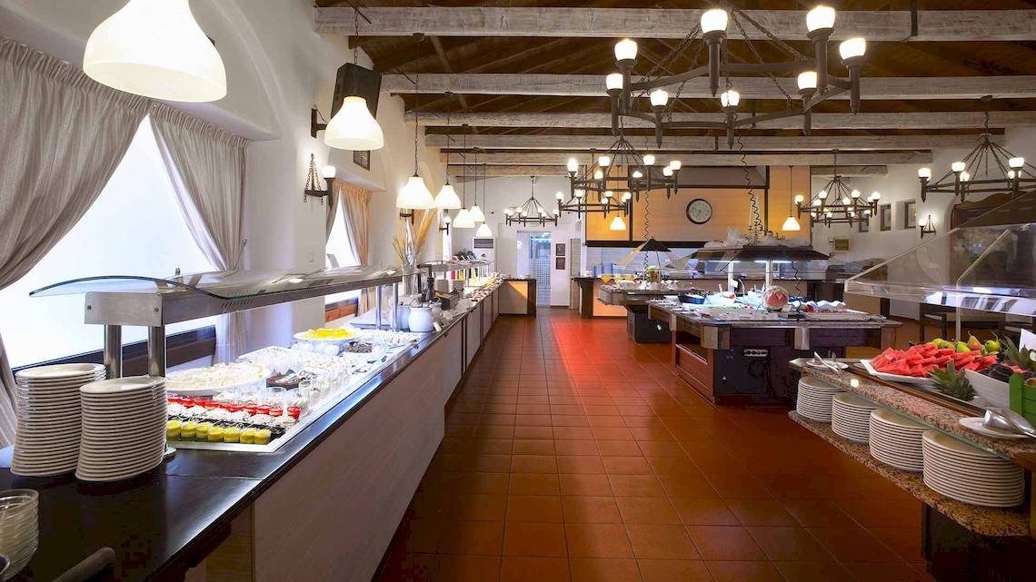 Restaurant im Acrotel Athena Pallas Hotel mit Speisenbuffet und roten Bodenfliesen.