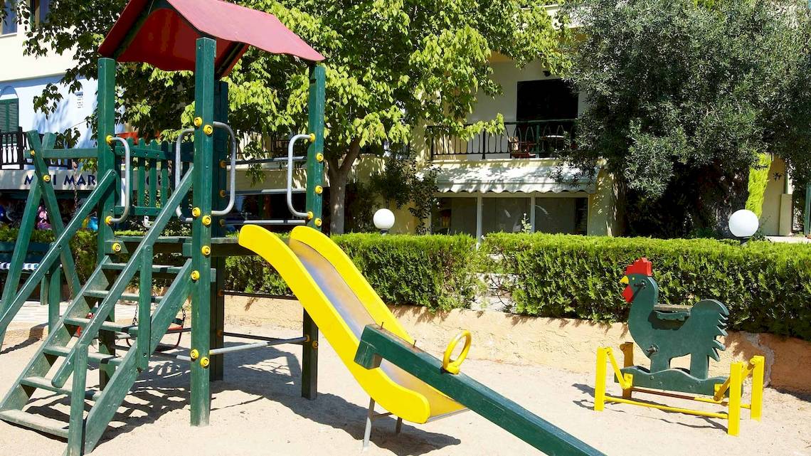 Spielplatz vor dem Hotel Acrotel Athena Pallas mit Rutsche und Hühnerfigur.