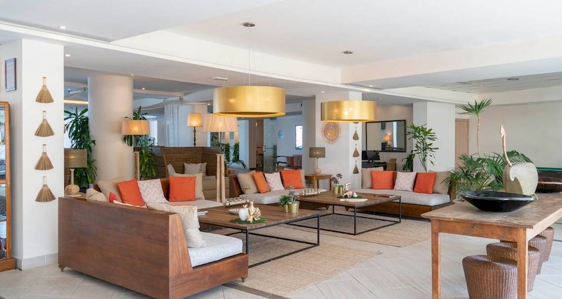 Lobby des Vincci Tenerife Golf Hotels mit Holzmöbeln, orangen Kissen und goldenen Lampen.