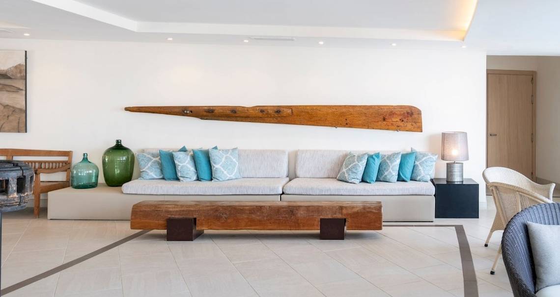 Wohnzimmer des Vincci Tenerife Golf Hotels mit weißen Wänden, einer großen Couch, Holztisch und bunten Kissen.