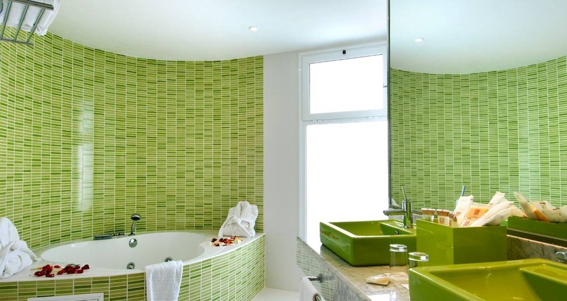 Badezimmer im Vincci Tenerife Golf Hotel mit grünen Wänden, Badewanne und grünen Waschbecken.