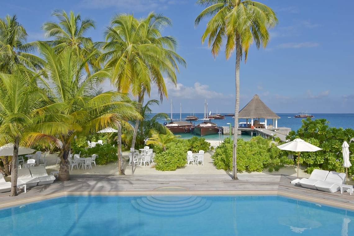 Außenbereich des Safari Island Resorts mit Pool, Liegestühlen und Palmen.