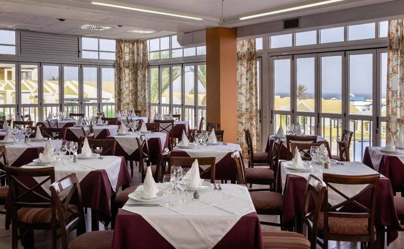 Innenansicht des Restaurants im Club Caleta Dorada mit gedeckten Tischen und Blick auf den Außenbereich.