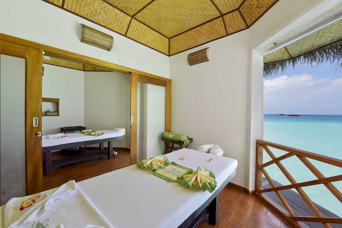 Massageraum im Safari Island Resort mit Blick auf das Meer und zwei Massagetischen.