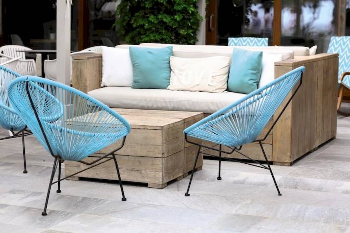 Eine Holzcouch mit blauen Sesseln auf einer Terrasse des Playa Golf Hotels.