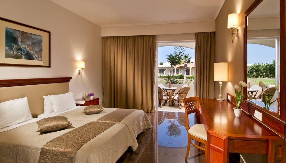 Hotelzimmer im Kipriotis Village Resort mit zwei Betten, Tisch, Stuhl und Balkon.