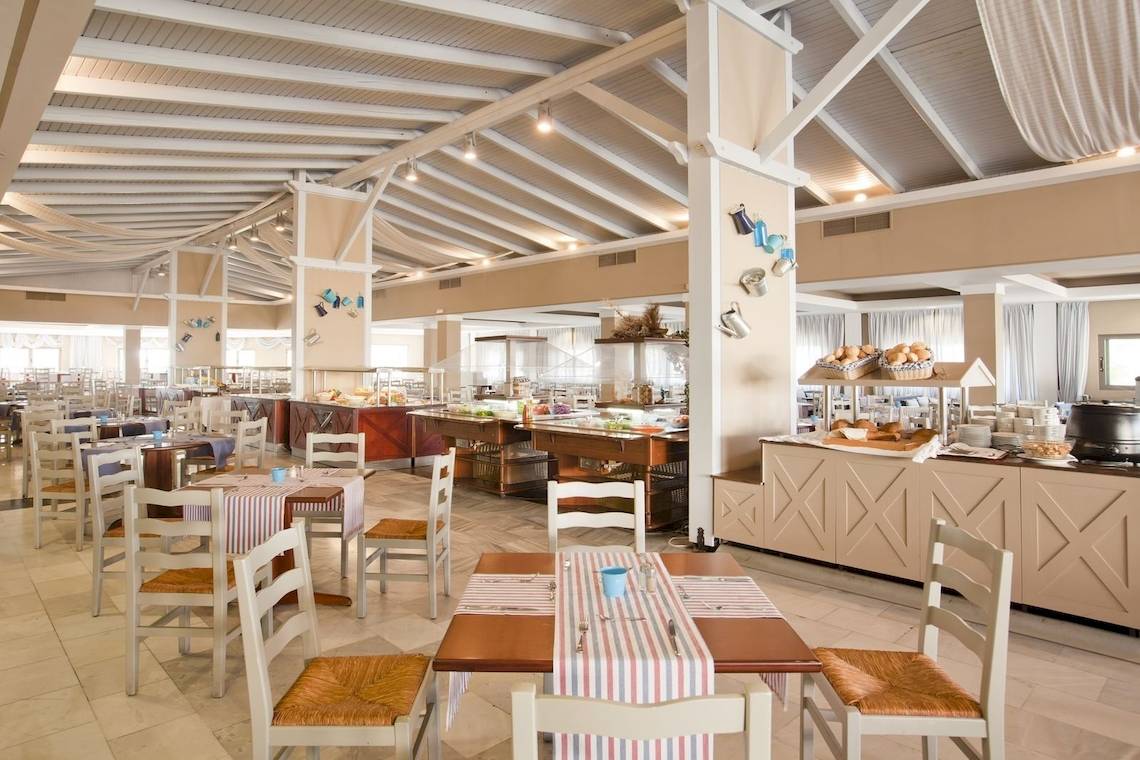 Innenansicht des Restaurants im Kipriotis Village Resort mit gedeckten Tischen und Buffet.