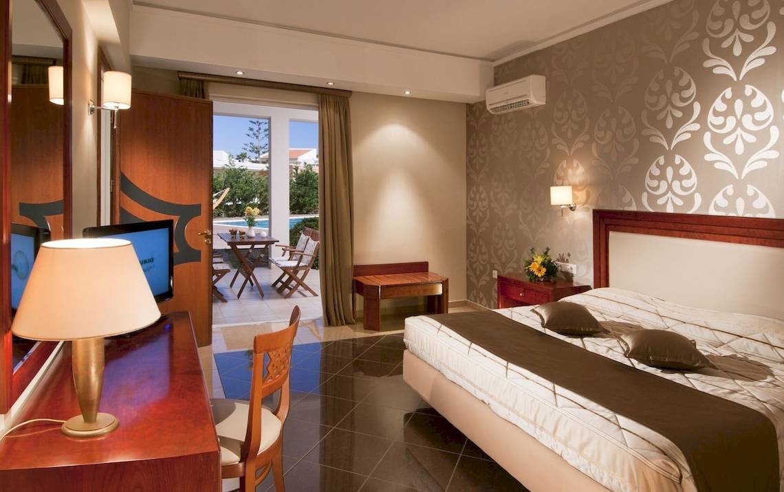Hotelzimmer im Kipriotis Village Resort mit Terrasse, Bett und Wohnzimmermöbeln.
