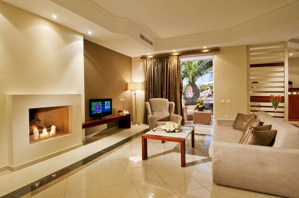 Wohnzimmer im Kipriotis Village Resort mit Fernseher, Kamin und Sofa.