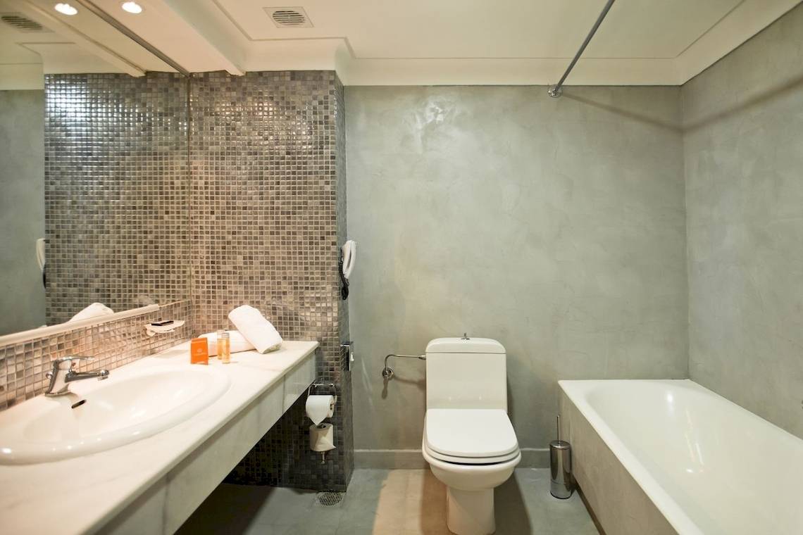 Badezimmer im Kipriotis Village Resort mit einer Dusche, Badewanne, Toilette und Waschbecken.