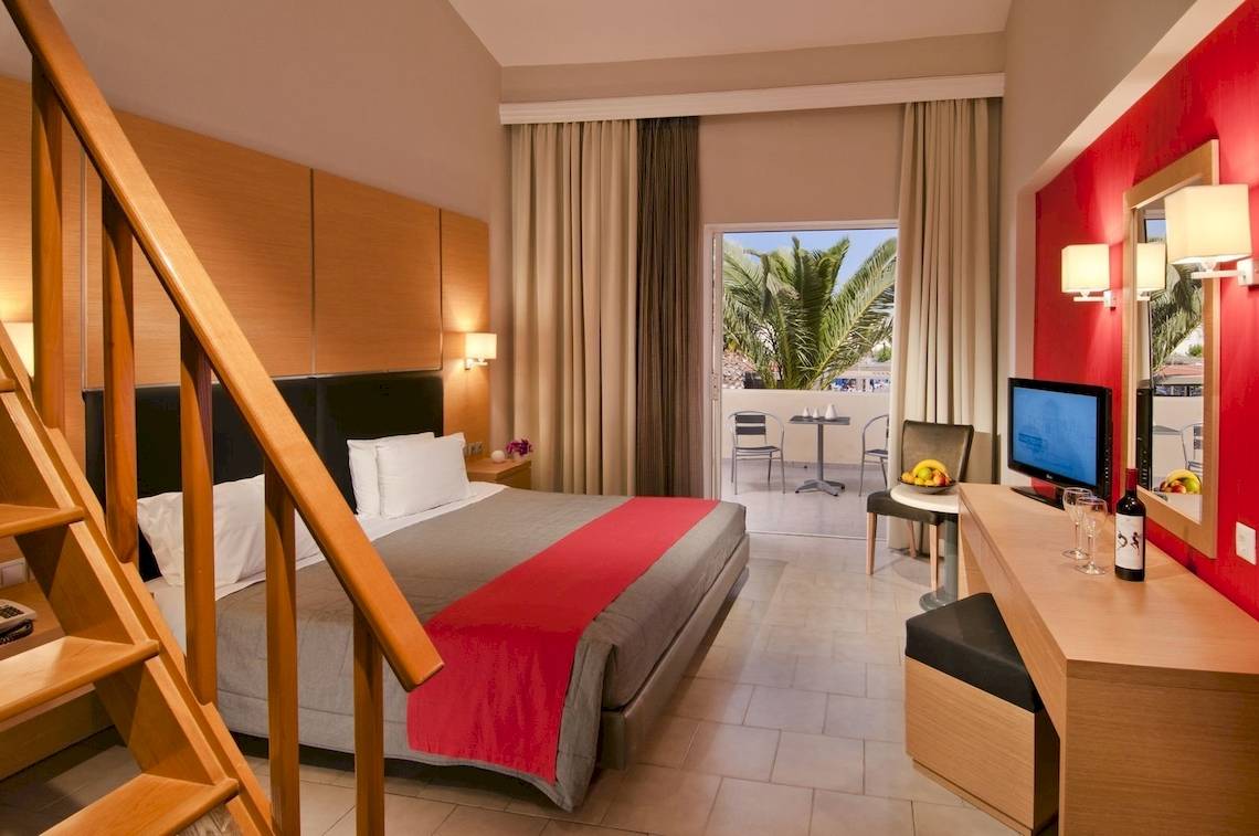 Hotelzimmer im Kipriotis Village Resort mit Bett, Balkon und Möbeln.