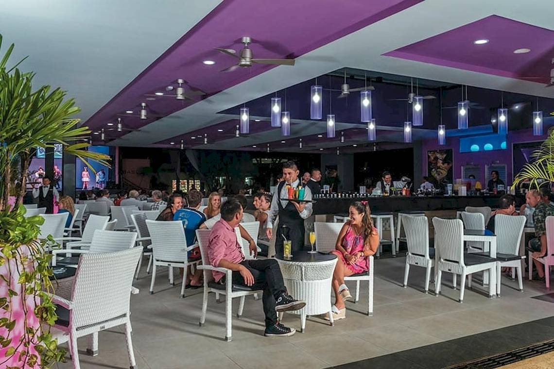 Gäste im Riu Lupita Hotel sitzen an Tischen und unterhalten sich.