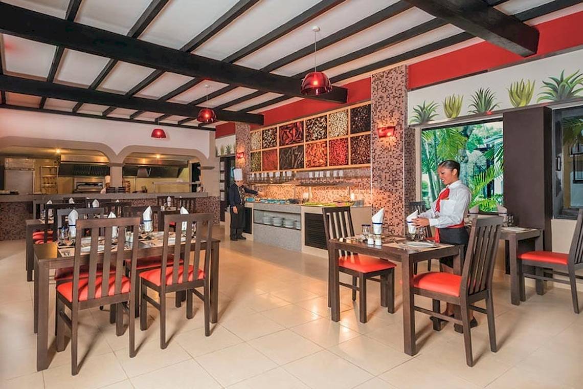 Innenansicht des Restaurants im Riu Lupita Hotel mit gedeckten Tischen und einer servierenden Mitarbeiterin.