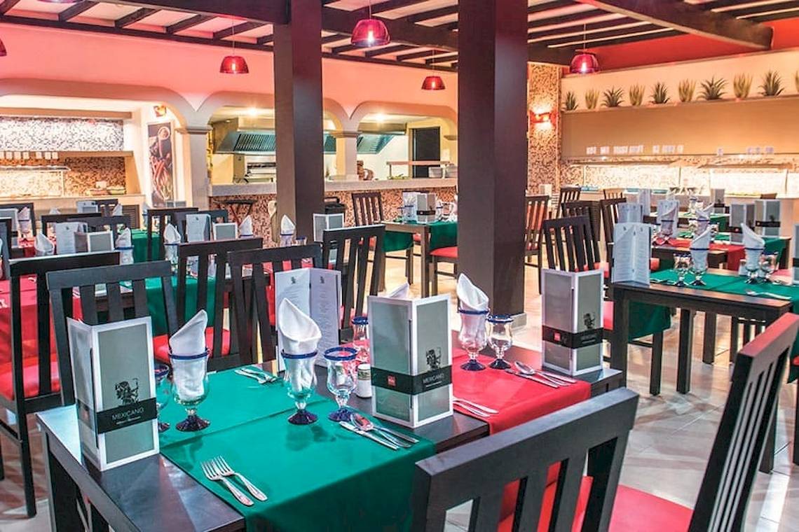 Innenansicht des Restaurants im Riu Lupita Hotel mit gedeckten Tischen und Stühlen.