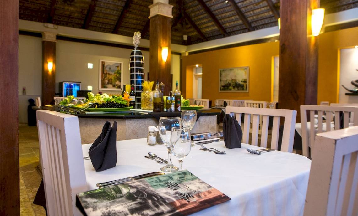 Speisesaal im Vista Sol Punta Cana Beach Resort & Spa mit gedeckten Tischen und dekorierten Speisenplatten.