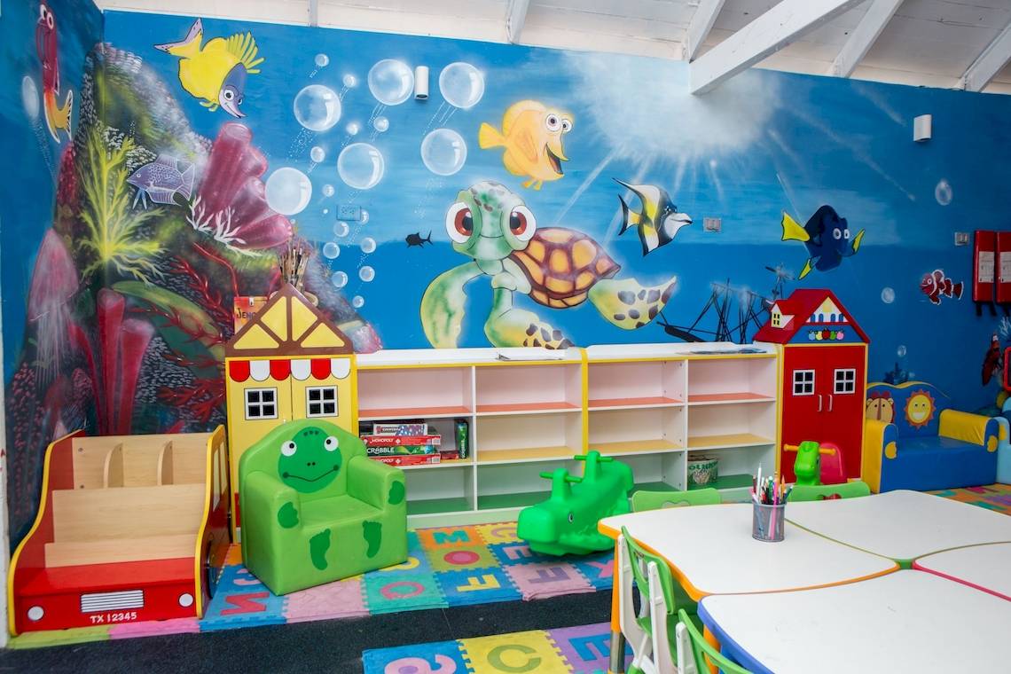 Kinderspielzimmer mit Unterwasserwelt-Wandmalerei, bunten Möbeln und Spielzeug.